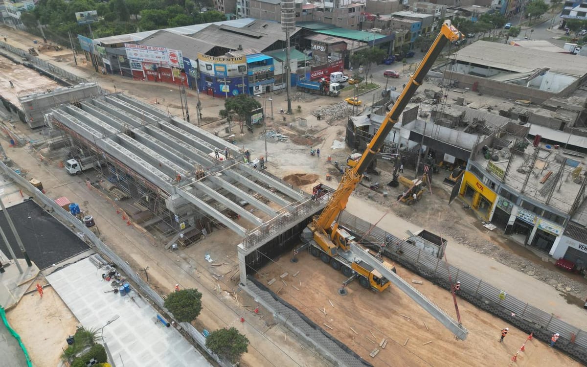 Grúa telescópica amarilla instalando vigas de concreto en una obra urbana.